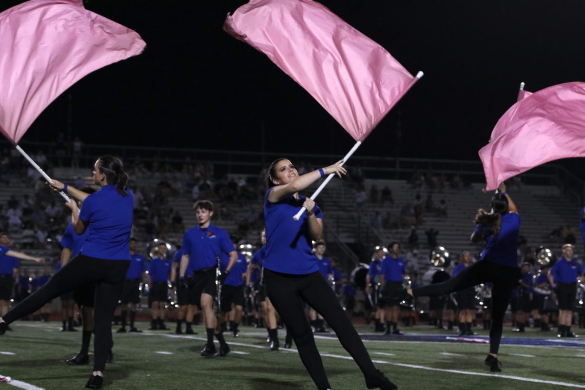 Senior Charlotte Scott performs with the color guard during the halftime show. The 2023 band show is called “Monomyth,” which translates to “one myth” and tells the story of multiple heroes moving toward the same goal.