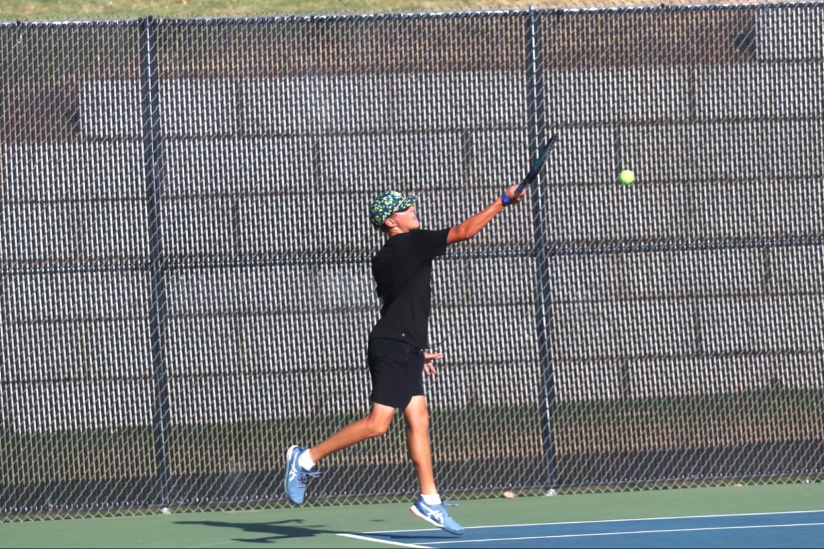 Sophomore Nigel Gudgeon leaps to return a shot from his opponent. His doubles partner was covering the corner of the net, leaving him with more area to cover.
