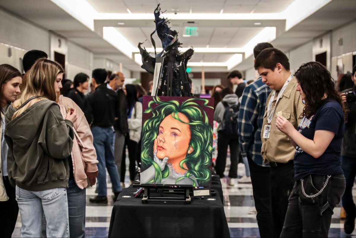 Students look through the art shown throughout the gallery. This table held paintings and abstract sculptures.