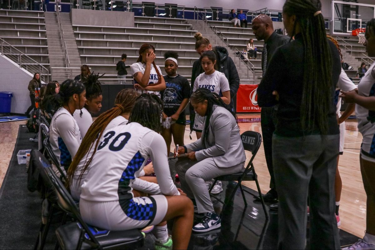 Head girls basketball coach Lisa Branch talks to the team about strategy before the game starts. She gave advice to the players, such as to swing or do screens when needed.
