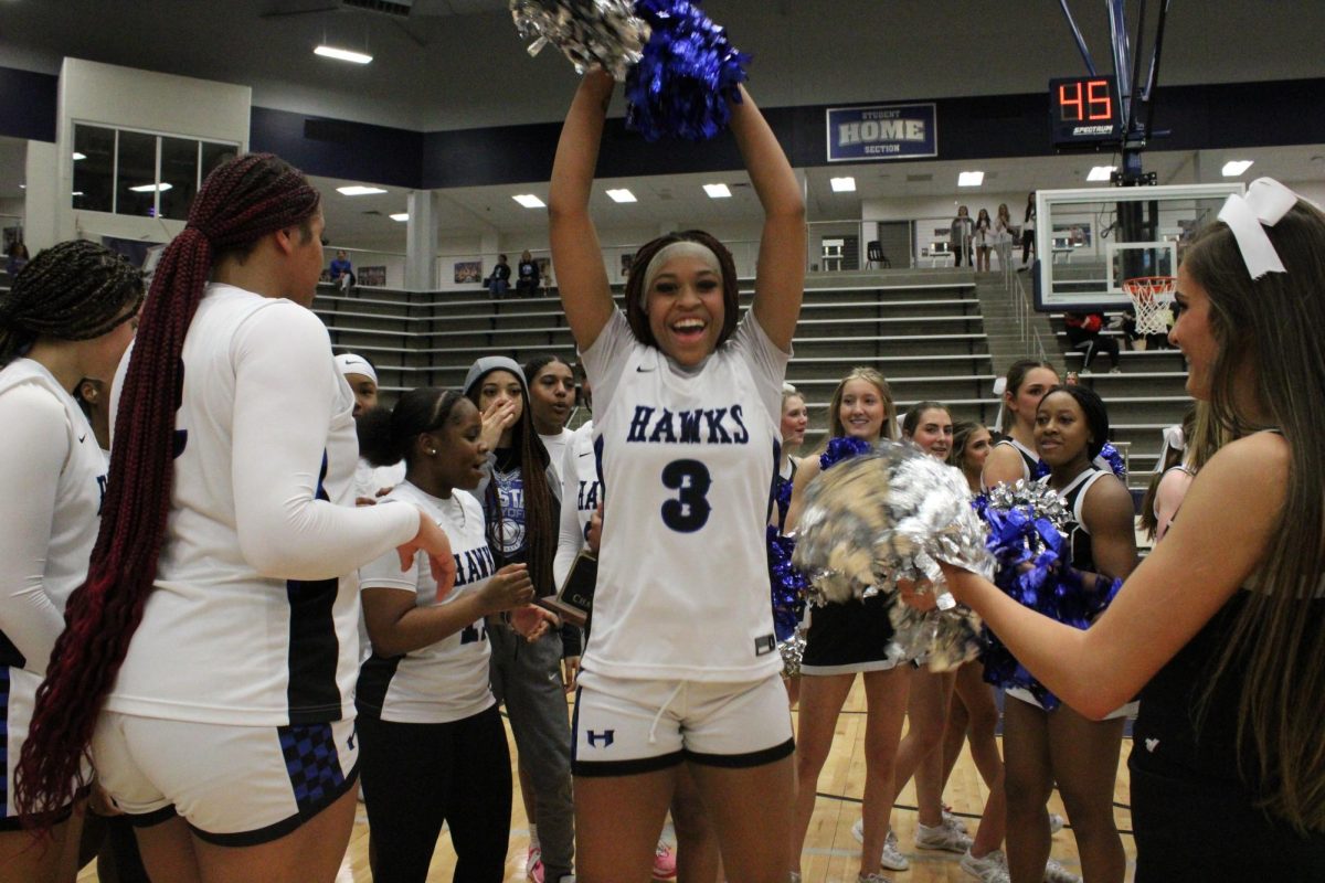 Forward Amaya Bell cheers as the team celebrates with cheerleaders. The cheerleaders were supporting the Lady Hawks the entire game with various chants and routines. 