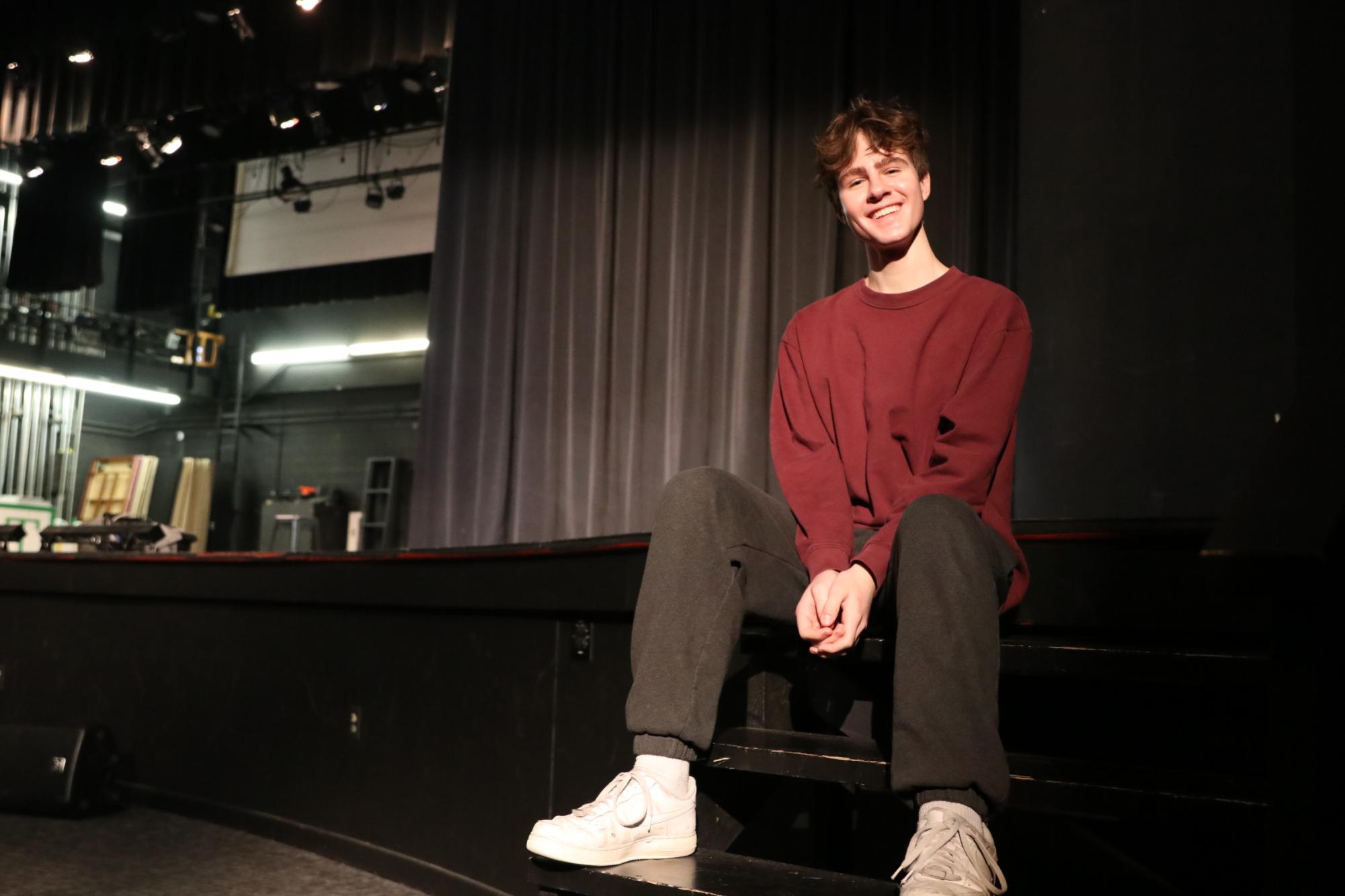 Senior Max Turman poses on the proscenium stage in the auditorium. The fine arts department recently performed “Matilda” on this stage, in which Turman played the role of Mr. Wormwood.