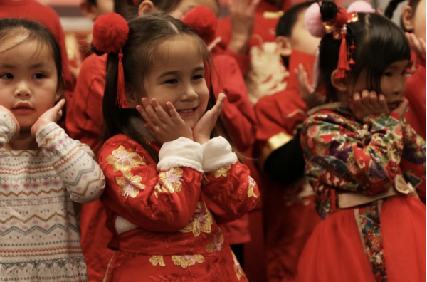 Elementary students from Sun Ray Chinese school perform a traditional Mandarin song and dance for the guests. They are dressed in red or traditional clothing pieces such as a Qipao with a Chinese knot button; the knots represent happiness, luck, fortune and longevity. 