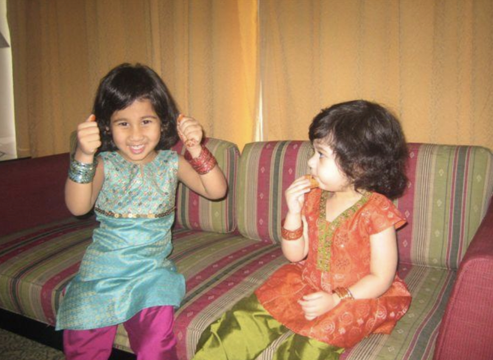 My sister and I sit on the couch and eat our favorite cookies. We are dressed in traditional clothing to celebrate the day of Eid. 