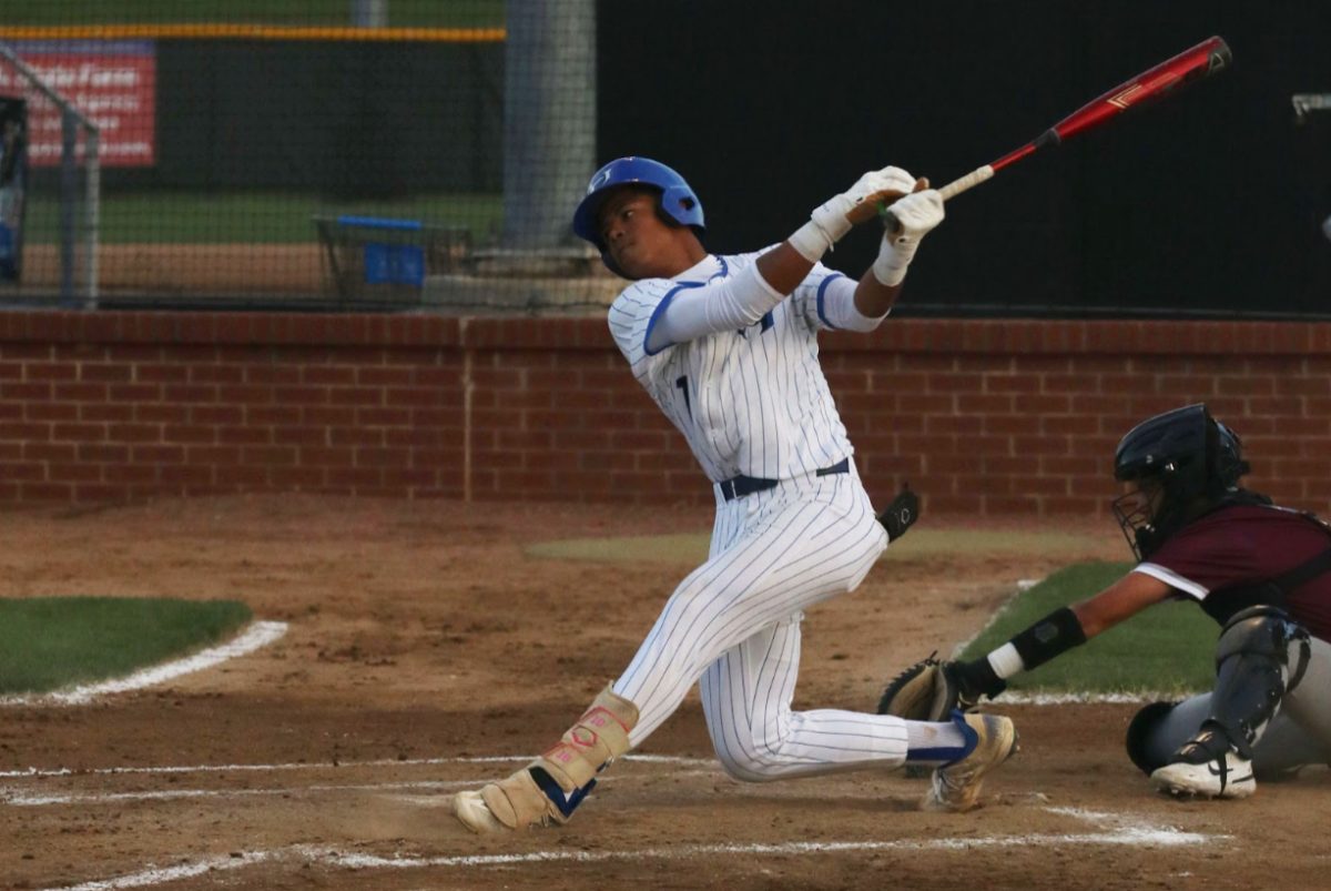 Third baseman Patrick Crayton hits the ball to the outfield before sprinting to first base in a game against Plano. The team won the game 3-2.