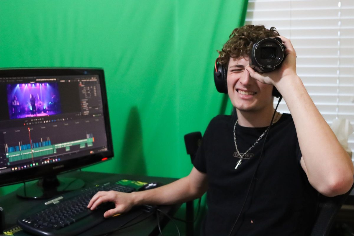 Senior Bogdan Slavu poses with his Sony FDR-AX53 camcorder. He uses this camera to record his vlog-intensive videos.