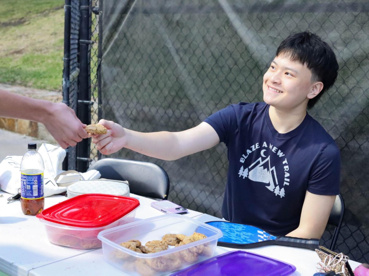 Sophomore Bill Jiang hands a salted caramel cookie to a spectator during a pickleball tournament Mar. 28. “Mind Bites” and “The Smile Project” partnered together to host the pickleball tournament and had 29 teams sign up to compete.